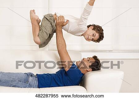 Man playing with his son on a couch View Large Photo Image Stock Photography - Man playing with his son on a couch. Fotosearch