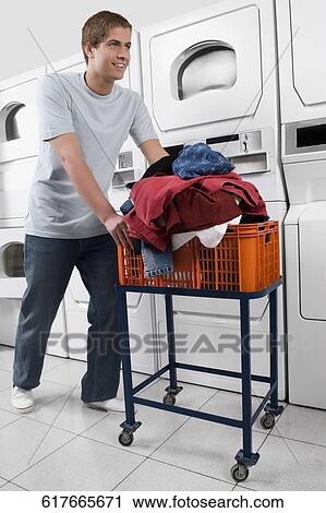 Man pushing a laundry basket in a laundromat View Large Photo Image Stock Image - Man pushing a laundry basket in a laundromat. Fotosearch