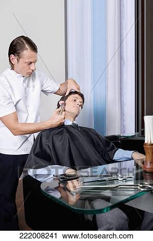 Man receiving a haircut in a salon View Large Photo Image Stock Image - Man receiving a haircut in a salon. Fotosearch