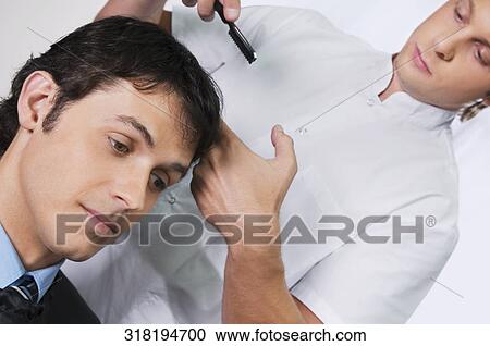 Stock Image - Man receiving a haircut in a salon. Fotosearch
