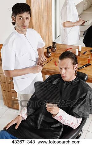 Stock Image - Man receiving a haircut in a salon. Fotosearch