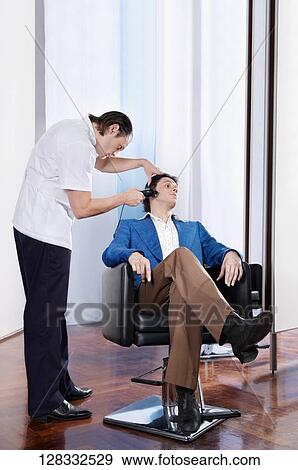 Man receiving a haircut in a salon View Large Photo Image Stock Photo - Man receiving a haircut in a salon. Fotosearch