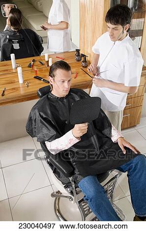 Man receiving a haircut in a salon View Large Photo Image Stock Photo - Man receiving a haircut in a salon. Fotosearch