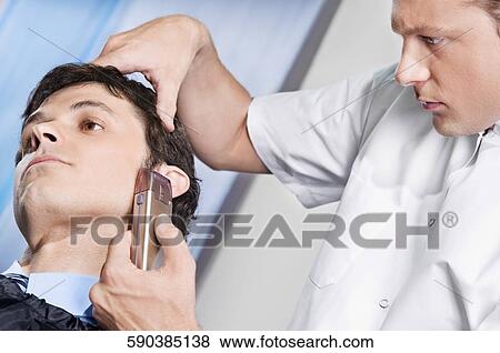 Stock Photo - Man receiving a haircut in a salon. Fotosearch