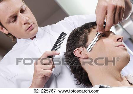 Man receiving a haircut in a salon View Large Photo Image Stock Photo - Man receiving a haircut in a salon. Fotosearch