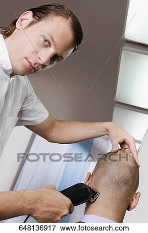 Man receiving a haircut in a salon View Large Photo Image Stock Photo - Man receiving a haircut in a salon. Fotosearch