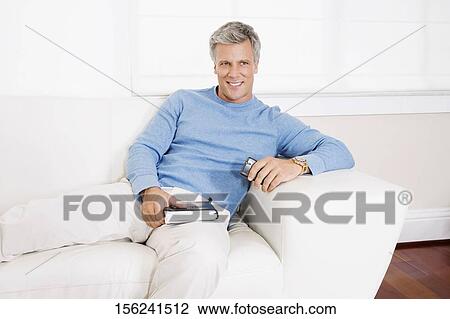 Stock Image - Man reclining on a couch. Fotosearch