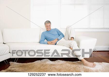 Man reclining on a couch View Large Photo Image Stock Photo - Man reclining on a couch. Fotosearch