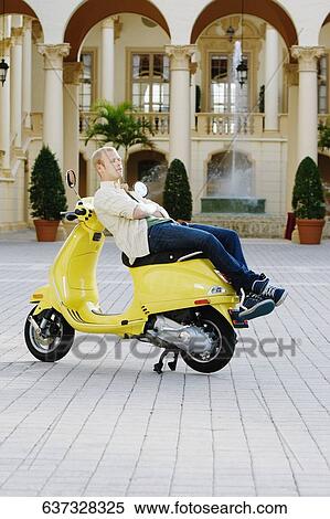 Man reclining on a moped in front of a hotel building, Biltmore Hotel, Coral Gables, Florida, USA View Large Photo Image Stock Photography - Man reclining on a moped in front of a hotel building, Biltmore Hotel, Coral Gables, Florida, USA. Fotosearch