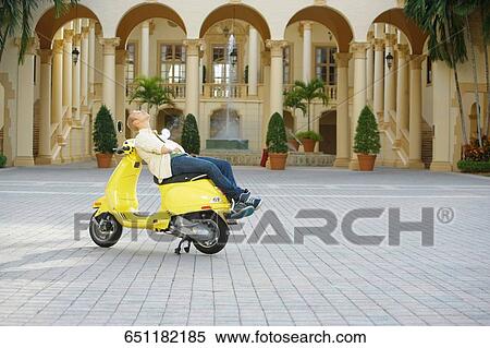 Man reclining on a moped in front of a hotel building, Biltmore Hotel, Coral Gables, Florida, USA View Large Photo Image Stock Photography - Man reclining on a moped in front of a hotel building, Biltmore Hotel, Coral Gables, Florida, USA. Fotosearch