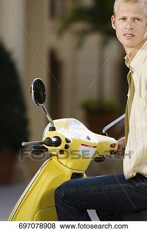 Stock Photo - Man sitting on a moped and thinking, Biltmore Hotel, Coral Gables, Florida, USA. Fotosearch