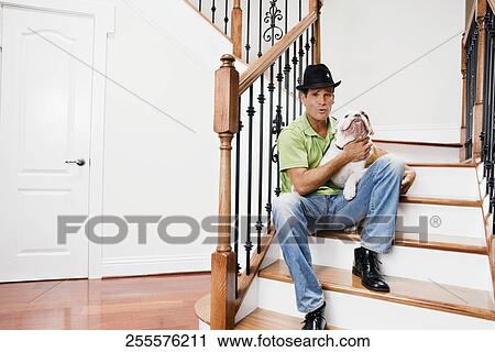 Man sitting on a staircase and carrying his dog View Large Photo Image Stock Image - Man sitting on a staircase and carrying his dog. Fotosearch