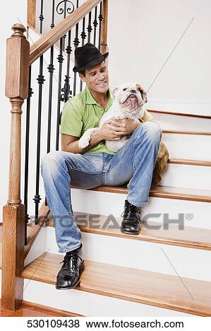 Man sitting on a staircase and carrying his dog View Large Photo Image Stock Photo - Man sitting on a staircase and carrying his dog. Fotosearch
