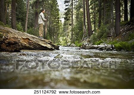 Stock Image - Man standing at the riverside. Fotosearch
