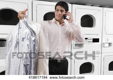Man talking on a mobile phone and holding shirts View Large Photo Image Picture - Man talking on a mobile phone and holding shirts. Fotosearch