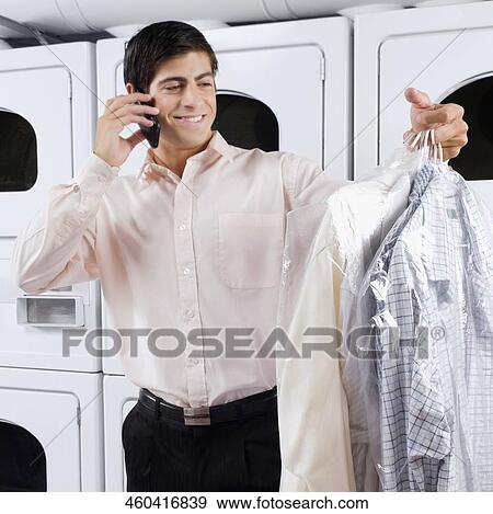 Man talking on a mobile phone in a laundromat View Large Photo Image Stock Photo - Man talking on a mobile phone in a laundromat. Fotosearch
