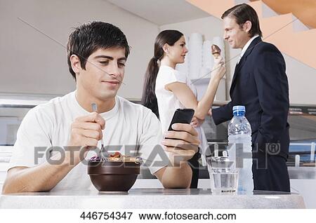 Man text messaging on a mobile phone in an ice cream parlor View Large Photo Image Stock Photo - Man text messaging on a mobile phone in an ice cream parlor. Fotosearch