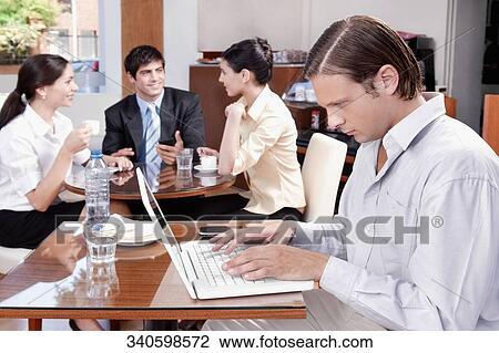 Stock Image - Man using a laptop in a restaurant. Fotosearch