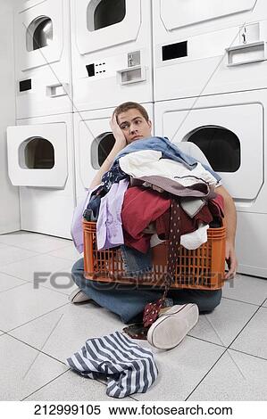 Stock Photography - Man with a basket in a laundromat. Fotosearch