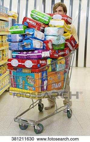 Man with a shopping cart loaded with diapers in a supermarket View Large Photo Image Stock Image - Man with a shopping cart loaded with diapers in a supermarket. Fotosearch