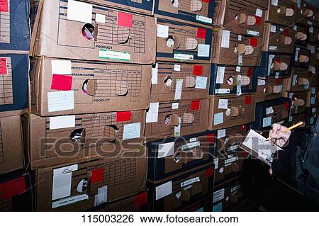 Stock Photograph - Man writing on a clipboard in a warehouse, Miami, Florida, USA. Fotosearch