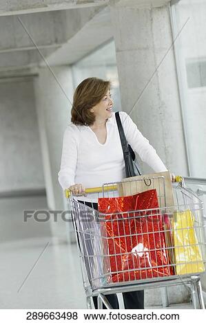 Mature woman holding a shopping cart View Large Photo Image Stock Photo - Mature woman holding a shopping cart. Fotosearch