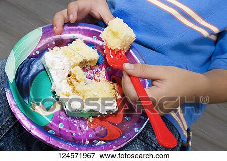 Stock Photo - Mid section view of a boy eating a cake. Fotosearch