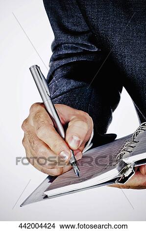 Picture - Mid section view of a businessman writing on a spiral notebook. Fotosearch