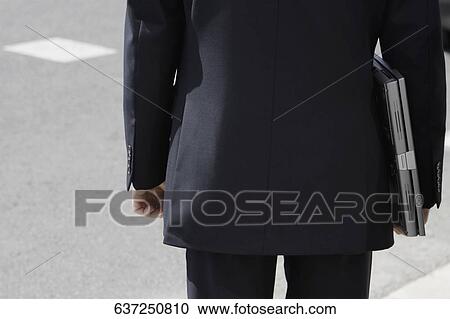 Mid section view of a businessman carrying a laptop View Large Photo Image Stock Image - Mid section view of a businessman carrying a laptop. Fotosearch
