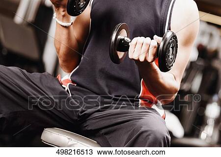 Mid section view of a young man exercising with dumbbells View Large Photo Image Stock Image - Mid section view of a young man exercising with dumbbells. Fotosearch