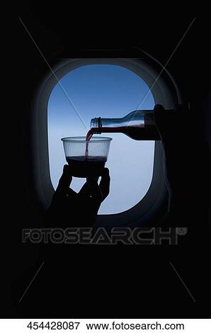 Person pouring wine into a glass in front of an airplane window View Large Photo Image Stock Photo - Person pouring wine into a glass in front of an airplane window. Fotosearch