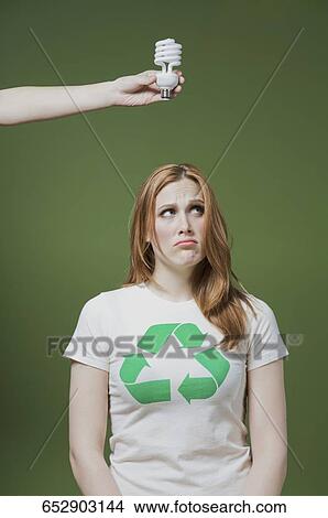 Person's hand holding a light bulb above a woman's head View Large Photo Image Picture - Person's hand holding a light bulb above a woman's head. Fotosearch