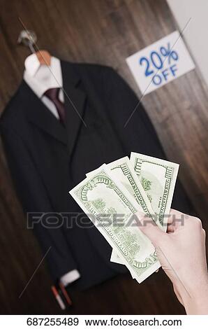 Stock Photo - Person's hand holding currency notes in a clothing store. Fotosearch