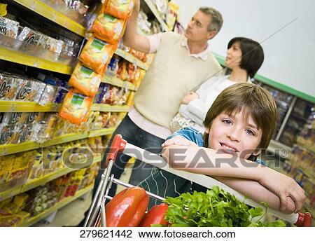 Portrait of a boy in a supermarket with his parents shopping behind him View Large Photo Image Stock Image - Portrait of a boy in a supermarket with his parents shopping behind him. Fotosearch