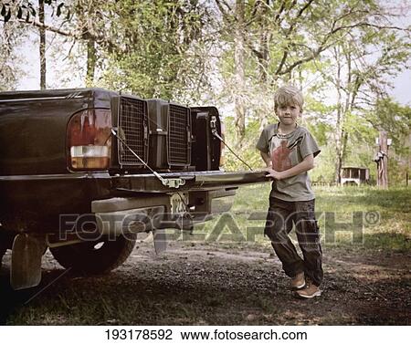 Stock Image - Portrait of a boy leaning against a vintage car. Fotosearch