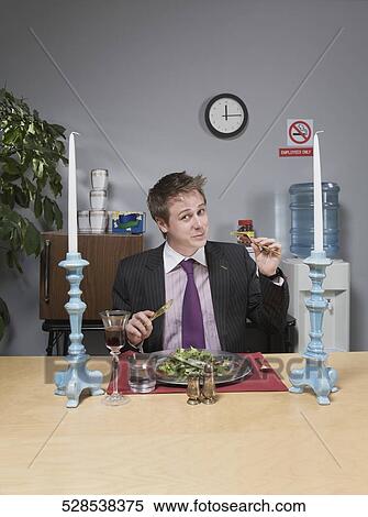 Stock Photography - Portrait of a businessman having lunch in the office. Fotosearch