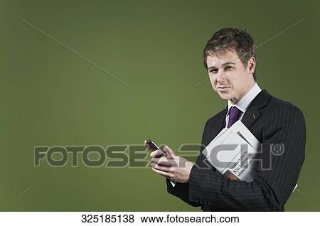 Stock Photo - Portrait of a businessman holding a mobile phone and a newspaper. Fotosearch