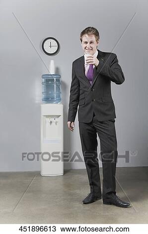 Portrait of a businessman standing near a water cooler View Large Photo Image Stock Image - Portrait of a businessman standing near a water cooler. Fotosearch