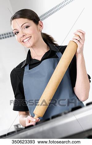 Portrait of a female chef holding a rolling pin and smiling View Large Photo Image Stock Image - Portrait of a female chef holding a rolling pin and smiling. Fotosearch