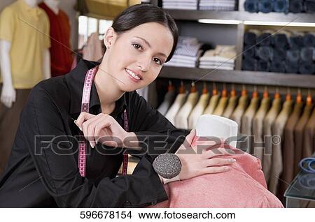 Picture - Portrait of a female tailor holding a tape measure. Fotosearch