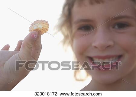 Portrait of a girl showing a seashell View Large Photo Image Stock Image - Portrait of a girl showing a seashell. Fotosearch