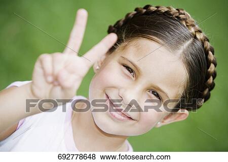 Stock Photo - Portrait of a girl showing a victory sign. Fotosearch