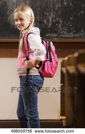 Stock Photograph - Portrait of a girl standing in a classroom and smiling. Fotosearch