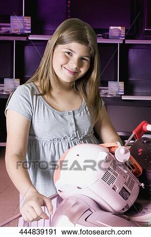 Stock Image - Portrait of a girl standing with a shopping cart in a supermarket. Fotosearch