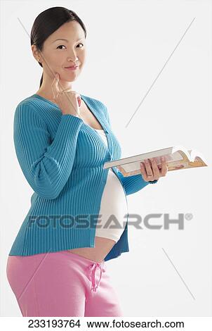 Portrait of a pregnant woman holding a book View Large Photo Image Picture - Portrait of a pregnant woman holding a book. Fotosearch