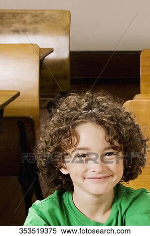 Stock Photography - Portrait of a schoolboy smiling in a classroom. Fotosearch