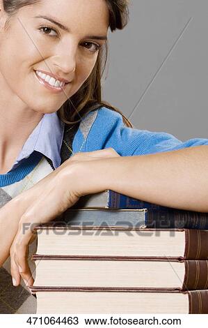 Stock Image - Portrait of a teacher with a stack of books in a classroom. Fotosearch