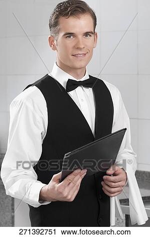 Portrait of a waiter holding a menu in a restaurant View Large Photo Image Stock Image - Portrait of a waiter holding a menu in a restaurant. Fotosearch