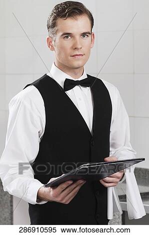 Portrait of a waiter holding a menu in a restaurant View Large Photo Image Stock Photography - Portrait of a waiter holding a menu in a restaurant. Fotosearch