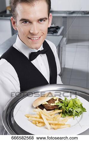 Portrait of a waiter holding a tray of snacks View Large Photo Image Stock Photo - Portrait of a waiter holding a tray of snacks. Fotosearch